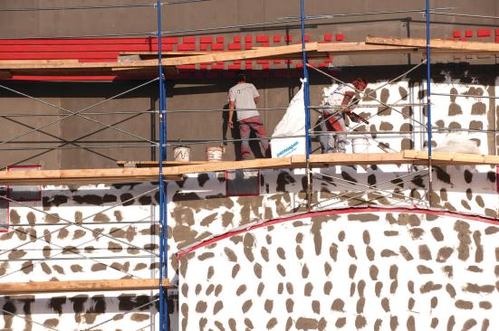 Workers stucco a new office building near the Huddlestonsâ house.