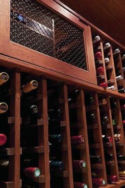 Behind a mesh grill is the WhisperKOOL self-contained chiller unit, which vents to the adjacent mechanical room, and keeps the temperature at an optimal 55 degrees. The wine racking system is by Vigilant Woodworks.