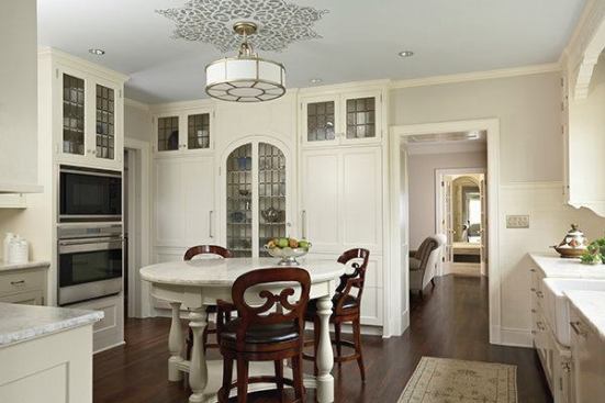 Attention to detail enhances the first-floor kitchen. According to the architects, the room has a circular motif with a round table topped with the same natural iceberg quartzite as the perimeter countertops, and "other period touches include the art-glass doors and ceiling stencil."