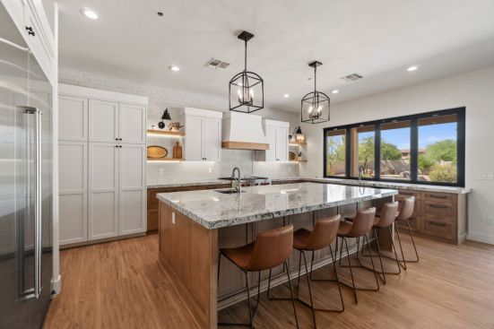 Lighting is layered with recessed cans, sconces, pendants, and under-shelving lights.