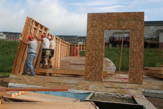 The crew hoists wall panels, featuring staggered studs, into place.
