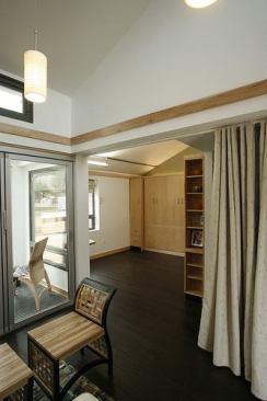 The Interlock House's central living space opens to gardens north and south; the semi-private bedroom includes a Murphy bed that folds up to provide room for the home office.