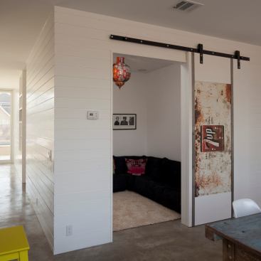 The rustic feel of this barn door–inspired installation is enhanced with the addition of reclaimed signage. The home, designed by Austin, Texas–based Alterstudio Architects, was crafted to celebrate its owners’ eclectic tastes, combining modern elements, such as honed concrete flooring, with vintage charm.
