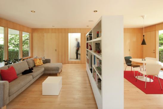 A white freestanding bookshelf divides the living and dining areas.  