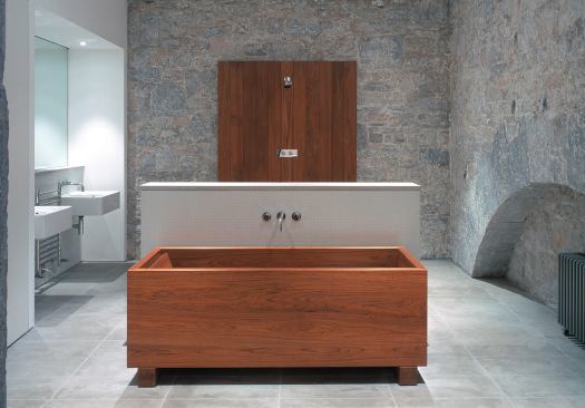 Clean, rectilinear forms complement the bath’s stone walls. The limestone floor, sleek washbasins, and handmade teak bathtub and shower panel lend a crisp, luxurious look.