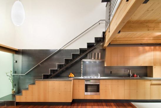 The metal stair leads from the second-floor main living space to a reading loft. Custom cabinetry throughout the home stores kitchen and laundry supplies, as well as other secrets.