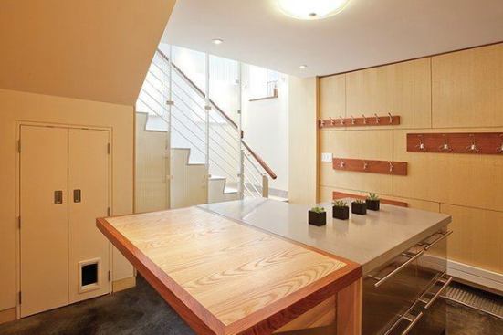 A folding side table adds extra island work space when it’s lifted. Hooks on the wall maximize storage. There’s even room for skis to rest, with a drain along the floor.