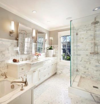 A large assembly in a relatively compact room, the frameless glass shower stall virtually disappears, allowing the marble wall tile inside to read through.