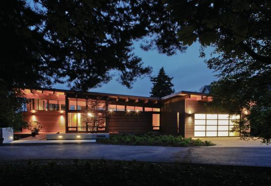 The house is oriented east-west, with openings at the roof’s high end that allow for passive cooling. Post-and-beam construction is infilled with glass and lapped clear cedar siding, some of it painted. 