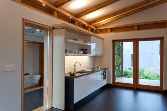 The kitchen opens to a pergola shaded by edible vines like snap peas and grapes.