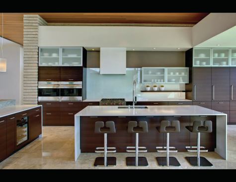 The Douglas fir ceiling and Mexican stone flooring continues throughout the house. Kitchen materials include wenge cabinetry, a back-painted glass backsplash, Caesarstone countertops, and an anodized aluminum bar.