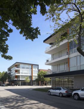Rising up from two vacant city lots, these twin mixed-use buildings form a portal to Chicago’s revitalized Wicker Park neighborhood. Ground floor retail space in each building steps back along Division Street (a busy retail corridor) while the residential units up top are outfitted with cantilevered decks that overlook a quieter side street and green space. The mostly glass facades are interspersed with cedar “fins” that add warmth, conceal the structural steel frame bracing, and carry over into the interiors of the residential units. 
Project: Division Street, Chicago 
Architect: Studio Dwell Architects 
Builder/Developer: Ranquist Development