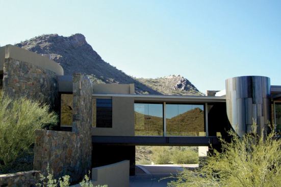 This desert home is nested, side-saddle-style, between two mountain slopes. Rather than choosing one view over the other, the architects went for both with a steel and glass bridge that connects opposite wings of the house. The transparent walkway frames views of the landscape on both sides and creates an entry portal for the driveway. 
Builder: Linthicum Corp., Scottsdale, Ariz. 
Architect: Allen + Philp Architects/Interiors, Scottsdale