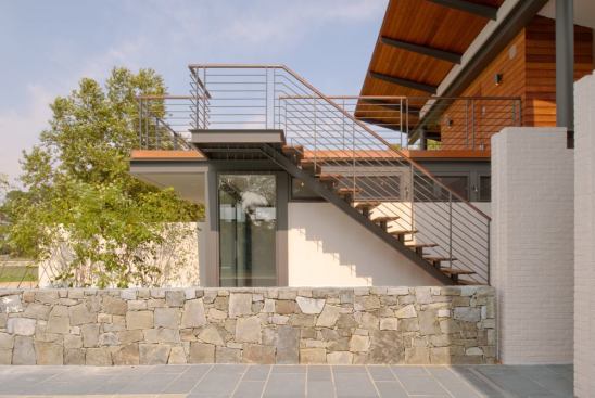 An existing stone wall separates the guest quarters and living pavilion. Stairs lead from the guest suite to a deck with river views.