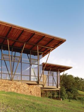 The central pavilion’s steel frame cantilevers over a curved retaining wall.