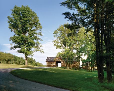 Visitors drive through the bays of a modern barn before arriving at the gravel court and house. The barn’s long face appears farmlike, while the short ends express the architectural layers of wall, fabricated truss, and stone water table. A cupola lets light into a workshop’s double-height interior.
