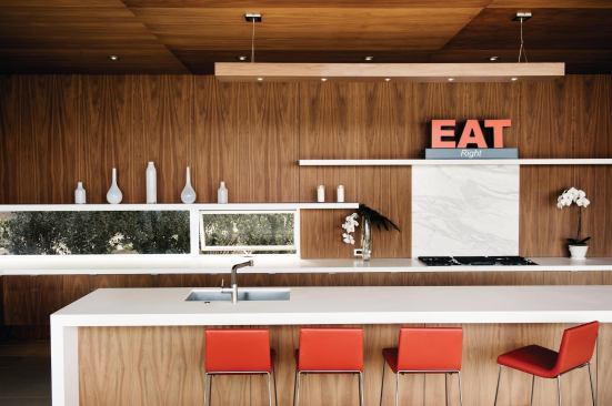 Walnut veneer clads the cabinets, walls, and ceiling, as well as the custom light fixture that hangs over the island.