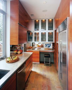 Light, reflective materials such as the aluminum-framed window and glass-and-aluminum cabinet doors extend the space visually.