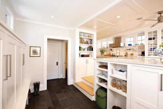 A paneled, bookshelf-lined opening links the kitchen to a storage-friendly mudroom.