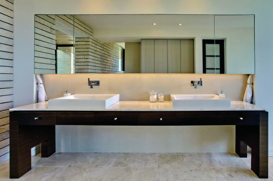 A double vanity is partially recessed into a niche with mirrored wall storage. 