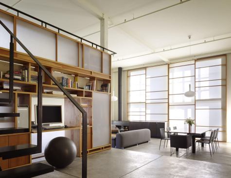 A San Francisco loft interior uses multipurpose moves such as a built-in shelving system and home office to maximize space efficiency.