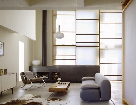A floor-to-ceiling fabric scrim filters the natural light flowing through the living room windows.