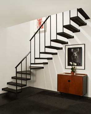 Cantilvered stairs that unite the two stories are made of cast iron treads from the Brooklyn Navy Yard. Steel supports for the staircase are concealed within the wall. 
