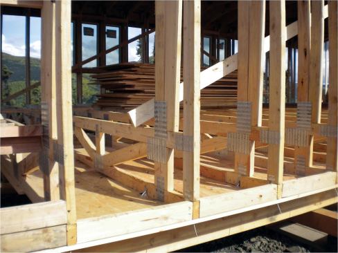 Blocking between trusses took the place of a conventional bottom plate; a 3/8-inch plywood skin beneath the bottom chords of the open-web floor assemblies served as backing for a thick layer of polyurethane spray foam. An open space between the upper surface of the foam and the subfloor above provided an unobstructed and frostproof plumbing chase.