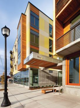 The volume facing a residential street is scaled down with balconies and a rainscreen system of fiber-cement panels and cedar accents.