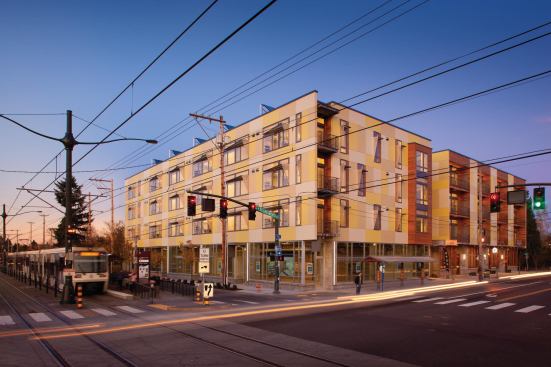 The west-facing façade along the busier street reads as a wall punctuated by triangular solar shades.