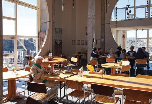 Soleri eats lunch in the café on the second floor of the mixed-use Crafts III building. Crafts III was constructed from 1972–77 to serve as a visitors center. It incorporates a gallery on the fourth floor, a bakery on the third, and housing on the first.