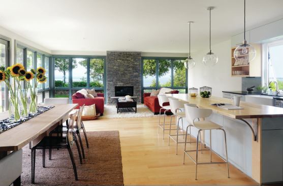 A window-lined great room serves as the heart of the 2,000-square-foot house. The south and west-facing glass allows for solar gain during Vermont's chilly winters. Locally quarried granite forms the fireplace surround.