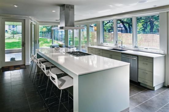 The white, glassy kitchen addition provides an airy counterpoint to the cool, dark living room in the existing house. 