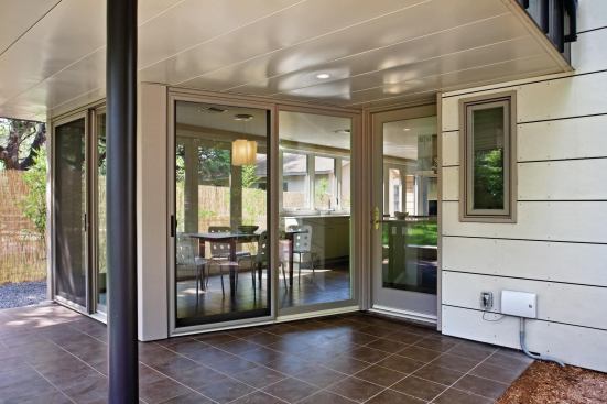The second story extends well beyond the glass walls of the new kitchen below to create a shady outdoor eating area.