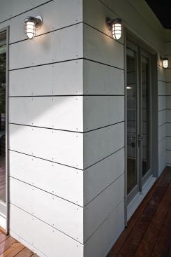 The scale and distinctive pattern of the fiber cement panels on the addition give it a contemporary feel, while the horizontal placement pays tribute to the traditional cypress planks on the existing structure.