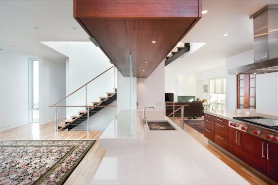 The island with the sink has a glass partition running partway across. The glass hides kitchen chaos from those in the dining room while letting light travel through the entire room. 