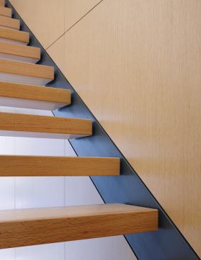 The steel stringers are set flush with the white oak paneling on one side and the plaster surface on the other.

