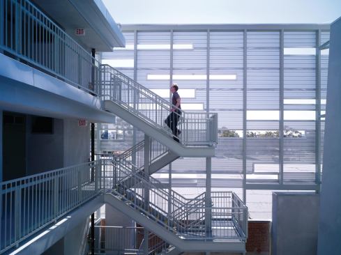 A perforated metal screen along the side of the building creates a dappled effect in the courtyards. The screen affords a degree of privacy while providing sightlines to the larger community. 

