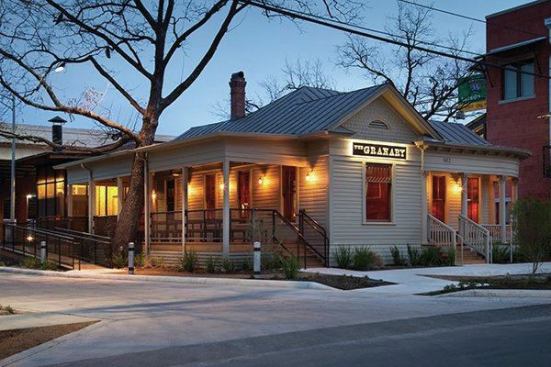 The developer had moved the structure before the renovation, and there was a large tree on the side of the building where the architect wanted to place a dining porch. The solution: frame the porch around the tree using reclaimed cypress. The new porch has cleaner lines than the original curved porch and its square columns contrast with the curved porch’s fluted round columns. The railing is raw steel. 