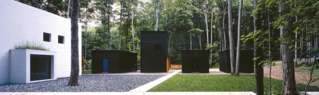 Four boxlike structures--three garages and a workshop--stand sentry duty between the parking area and the entry court.

