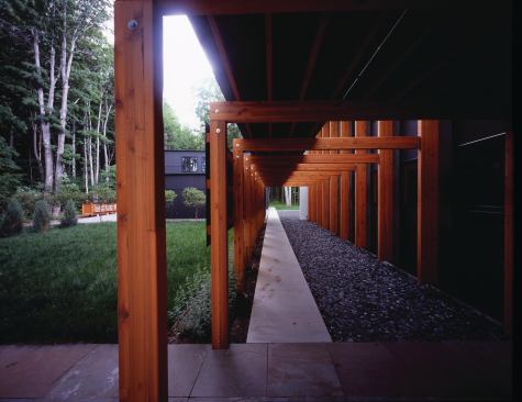 The entry trellis maintains the rhythm of the house's main structural frame.