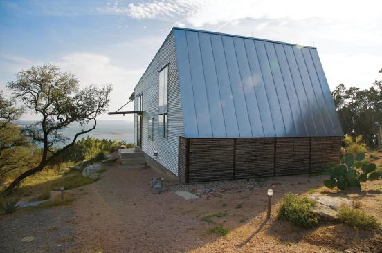 Raw, site-gathered juniper branches and standing-seam metal clad the back of the building.