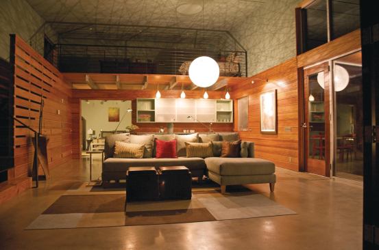 At night, a central light fixture casts shadow lines around the loft-like interiors.