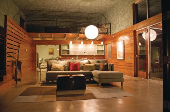 At night, a central light fixture casts shadow lines around the loft-like interiors.