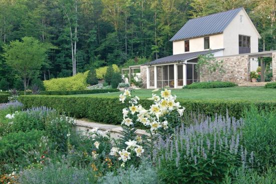 The rear garden's hawthorn allee aligns with the front door and leads to the sunken perennial border, which is shown here in bloom.