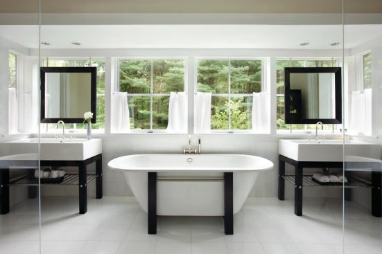 A suite of Waterworks fixtures matches the rooms clean lines and allows light and air to flow under the sinks and tub surround.