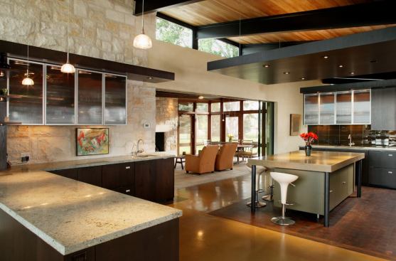 Southward-facing clerestory windows flood the kitchen with direct natural light throughout the day without adding a lot of heat. Glossy wood decking on the ceiling intercepts and channels the softened light into the space.