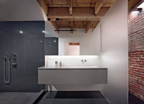 Floating cabinetry, an open shower, and bare-bones industrial materials play off each other all through the loft. 