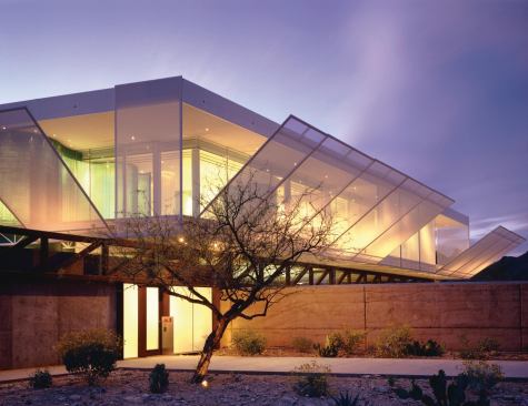 The ground floor’s massive rammed earth walls and exposed steel trusses contrast with the translucent box they support.