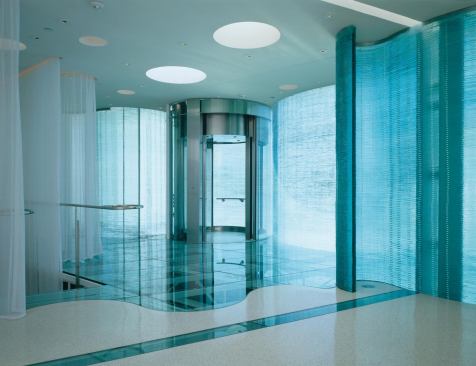 The second-floor residence features glass floors and serpentine stacked-glass partitions. 

